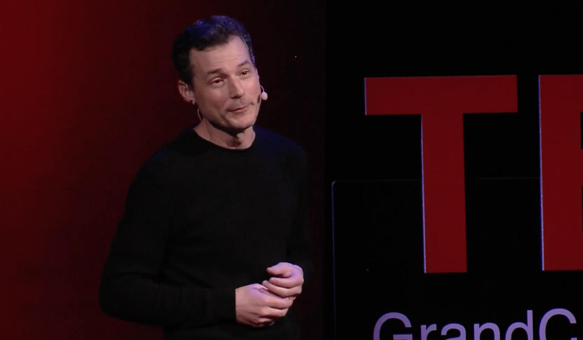 J. A. Speaking on stage with people in the front row.